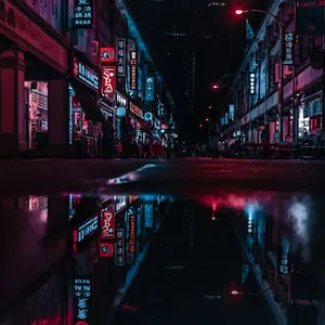 A wet street between buildings at night