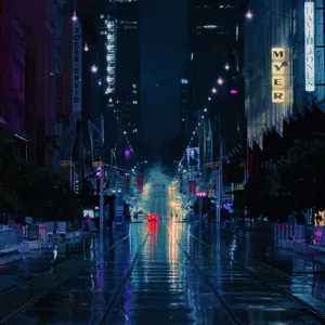 An empty road surrounded by lit buildings